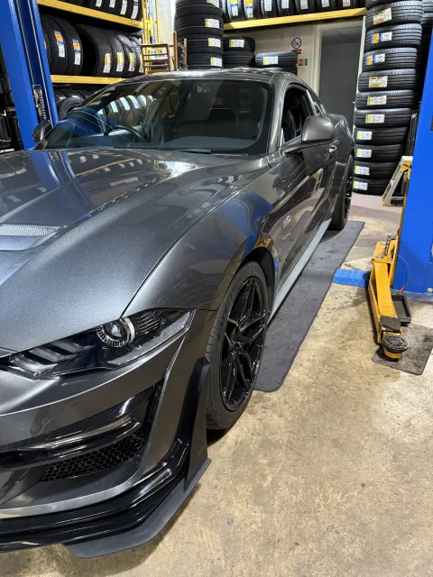 Grey Ford Mustang in the workshop with black alloy wheels and tyres fitted.